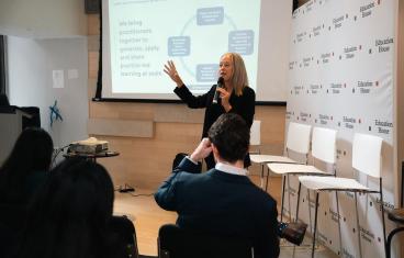 Wendy Kopp speaks into a microphone while presenting to an audience.
