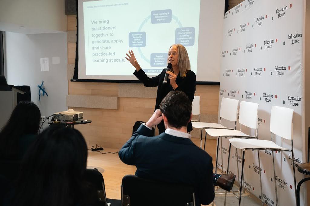 Wendy Kopp speaks into a microphone while presenting to an audience.